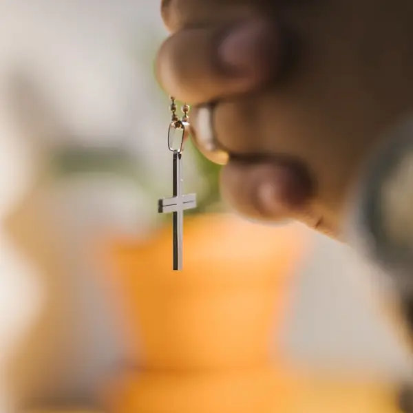 A hand holding a rosary with a crucifix.